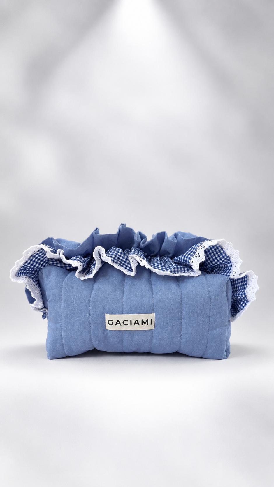A light blue quilted fabric pouch with a white and blue gingham ruffled trim and a white label reading 'GACIAMI' on the front, photographed against a soft white studio background.