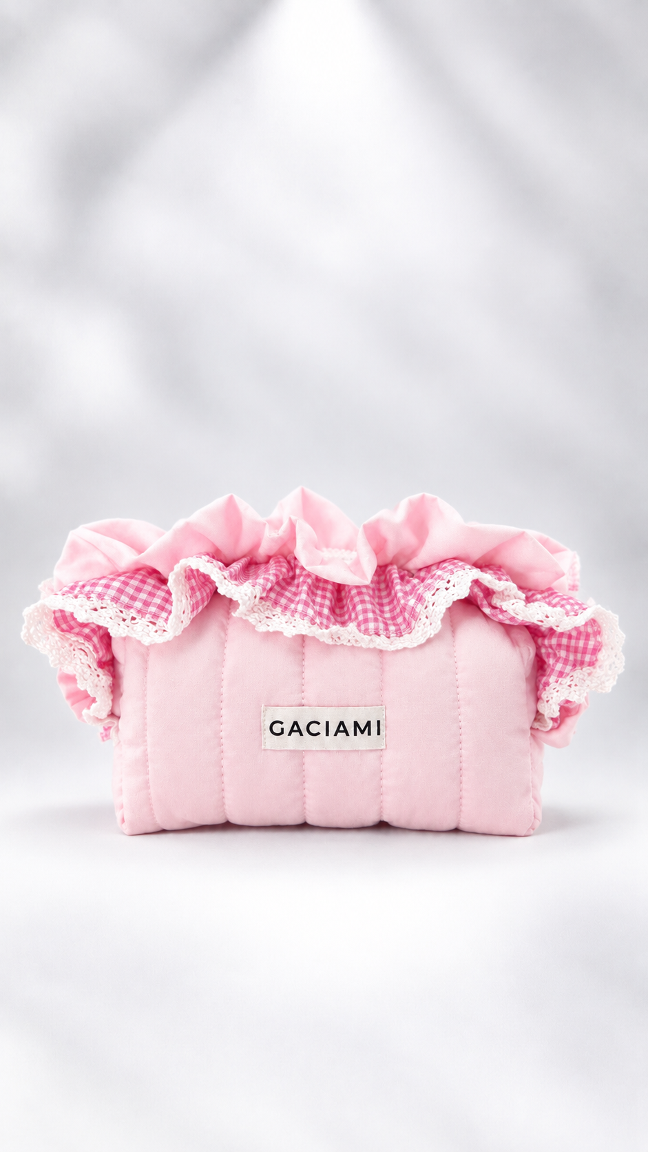 A pink quilted cosmetic pouch with ruffled trim, featuring a pink and white gingham pattern and a white lace edge. A small white label on the front reads 'GACIAMI'.