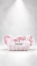 A light pink quilted cosmetic pouch with ruffled trim and a white label reading 'GACIAMI' in black text, photographed on a white studio background with a spotlight effect.