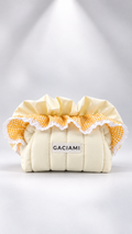A cream-colored quilted fabric pouch or organizer with a ruffled yellow and white gingham trim and a white lace edge. A small white label on the front reads 'GACIAMI'.