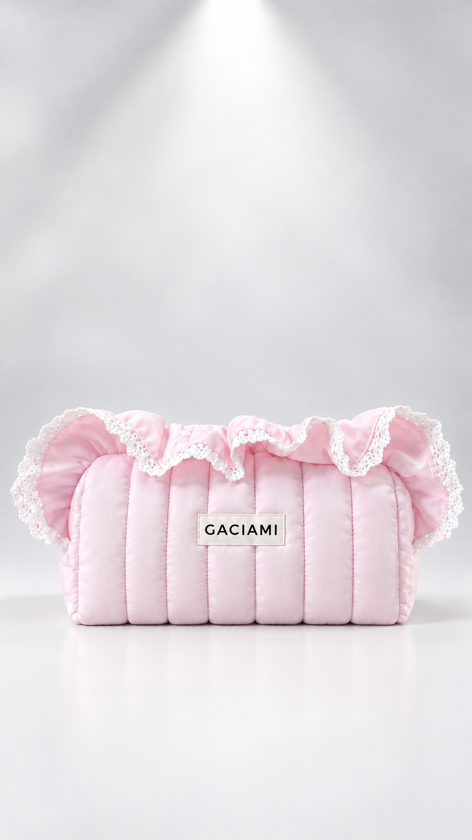 A light pink quilted puffer bag with white lace ruffles on the top, featuring a white rectangular label with the brand name 'GACIAMI' in black text, set against a clean white background with a spotlight effect.