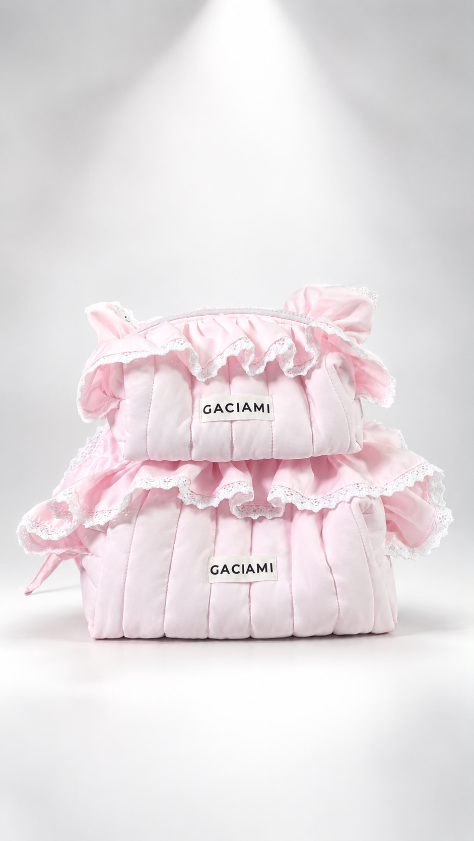 Three stacked light pink quilted pouches with ruffled trim and lace, each featuring a white label that reads GACIAMI, on a white studio background with a spotlight effect.